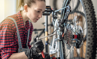 Woman is performing maintenance on mountain bike. Concept of fixing and preparing the bicycle for...