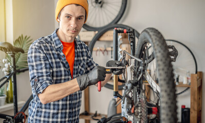 A male bicycle mechanic in the workshop disassembles a mountain bike and repairs it. Maintenance concept, preparation for the new season - 772738119