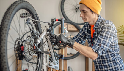 A male bicycle mechanic repairs a mountain bike in a workshop. The concept of preparation for the new season, repair and maintenance - 772738315