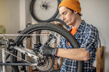 A male bicycle mechanic repairs a mountain bike in a workshop. The concept of preparation for the new season, repair and maintenance - 772738767