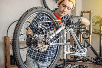 A male bicycle mechanic repairs a mountain bike in a workshop. The concept of preparation for the new season, repair and maintenance - 772739183