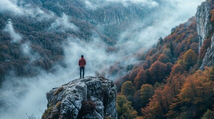 Man standing on the edge of a cliff in the autumn forest. - obrazy, fototapety, plakaty
