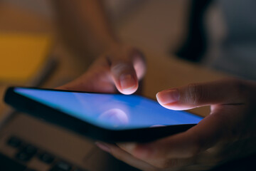 Close-up of hand holding smartphone device and typing text message on online social.