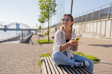 Young woman hipster sitting at city street , use cellophane, chatting with friends, have video call