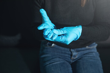 Caucasian woman wearing blue medical gloves.
