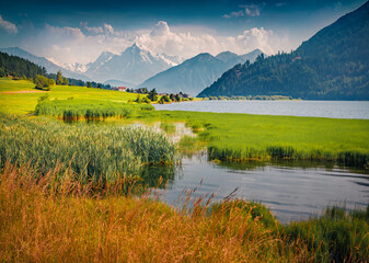 Wonderful summer view of Muta (Haidersee) lake. Picturesque morning scene of St Valentin auf der Haide village with snowy Tuckettspitze peak, Italy. Beauty of countryside concept background.