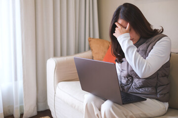 A woman get headache and stressed while working online on laptop computer at home