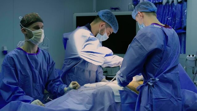 A team of doctors - surgeons performing a surgical operation in the operating room of a modern hospital department. Healthcare and medicine.