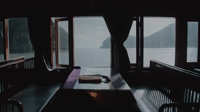 Empty table and chairs by a window on a ferry sailing along Lan Ha Bay In Vietnam 