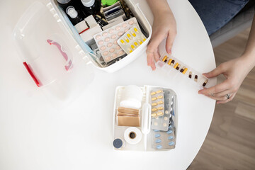 Closeup female hand placing medicament domestic first aid kit. Storage organization emergency supply