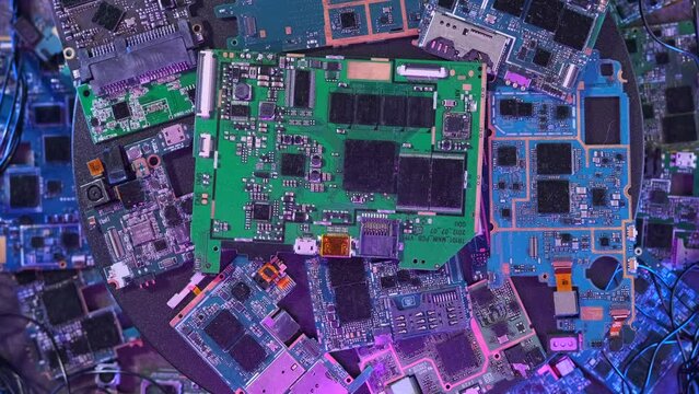 Many microchips surrounded by wires background in purple neon lights, rotation close-up, computer hardware and digital computing of big data.