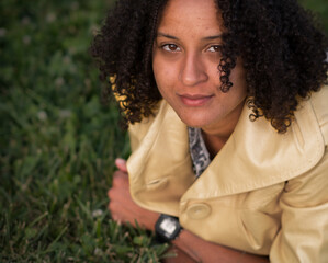 Portrait of African American young woman laying on grass and looking at camera