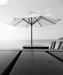 Beach umbrella, wooden table, black and white monochrome toned. Atmospheric mood