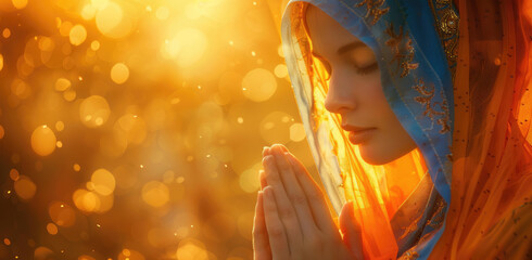 A beautiful young woman in prayer, with her hands clasped together and eyes closed against the backdrop of sunset light