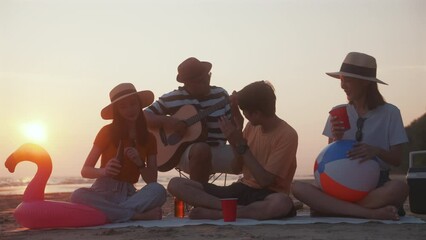 People vacation lifestyle journey concept. Happy asian diverse group friends having a picnic hang out and enjoy drinking liquor together on sea beach background outdoors during the sunset time.