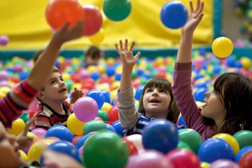 Fotobehang children in a ball pit, tossing colorful balls up © studioworkstock