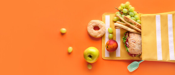 Naklejka na ściany i meble Lunch box bag with different tasty food on orange background
