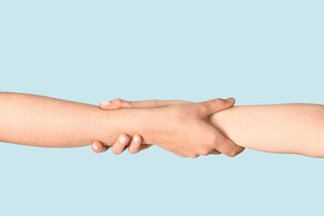 Women holding hands together on light blue background. Friendship concept