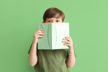 Little boy with book on green background. Children's Day celebration