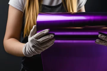 Foto op Canvas woman wearing gloves holding a metallic purple vinyl roll © studioworkstock
