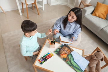 Little boy with psychologist drawing at table in office