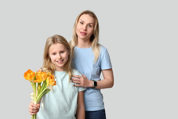 Cute little girl with her mom and bouquet for Mother's Day on white background