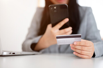 A businesswoman sitting at a table with her smartphone and a credit card, using a mobile banking app