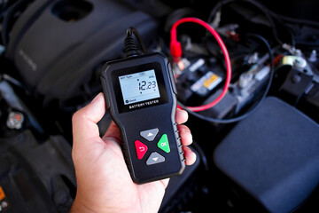 Battery tester in a auto mechanic hand for battery voltage or battery health analysis , Car...