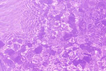 Purple water splashes on the surface ripple blur. Defocus blurred transparent pink colored clear calm water surface texture with splash and bubble. Water waves with shining pattern texture background