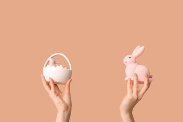 Female hands holding Easter basket with bunny on beige background