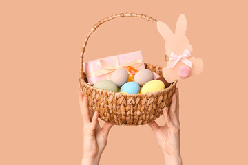 Female hands holding basket for Easter on beige background
