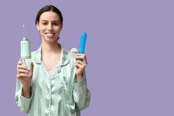 Beautiful young woman with oral irrigator, case and dental floss on lilac background
