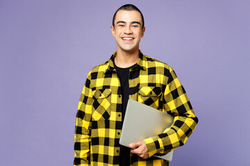 Young fun smiling happy smart IT middle eastern man wear yellow shirt casual clothes hold use work on laptop pc computer isolated on plain pastel purple background studio portrait. Lifestyle concept. - 772793944