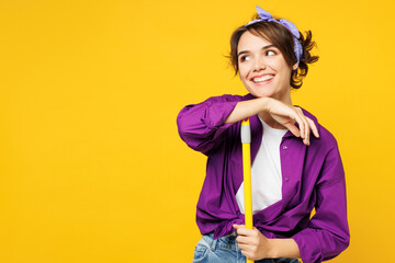 Young minded happy woman wear purple shirt casual clothes do housework tidy up hold in hand broom look aside on area mock up isolated on plain yellow background studio portrait. Housekeeping concept. - 772794501