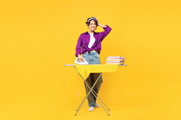 Full body young sad woman she wear purple shirt casual clothes do housework tidy up ironing clean clothes on board look camera isolated on plain yellow background studio portrait Housekeeping concept - 772794538