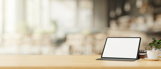 A tablet mockup with a wireless keyboard on a wooden table in a cosy, minimalist coffee shop.