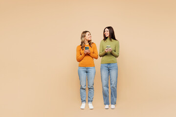Full body young friends two women wearing orange green shirt casual clothes together hold in hand...