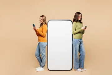 Foto op Canvas Full body young friend two women they wear orange green shirt casual clothes together big huge blank screen mobile cell phone smartphone do winner gesture with area isolated on plain beige background. © ViDi Studio