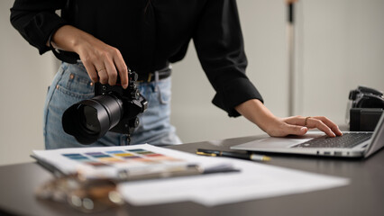 A cropped shot of a female photographer checking images on a laptop computer in a studio. © bongkarn