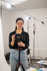 Fototapeta na wymiar A professional Asian female photographer is adjusting her DSLR camera on a tripod stand.