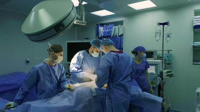 A team of doctors - surgeons performing a surgical operation in the operating room of a modern hospital department. Healthcare and medicine.