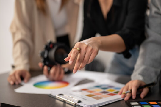A cropped image of a professional, experienced female photographer working with her team in the studio.