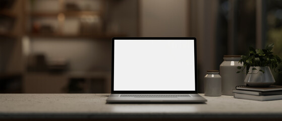 A close-up image of a white-screen laptop computer mockup on a desk in a modern dark room at night.