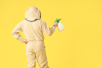 Male beekeeper with sprayer on yellow background, back view
