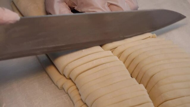 얇게 편 반죽을 칼국수 면 크기로 칼로 썰고 면에 묻은 밀가루를 털어내는 모습