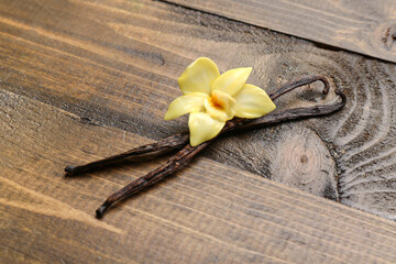 Aromatic vanilla sticks with flower on wooden background