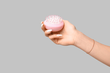 Female hand with pink hair brush on grey background