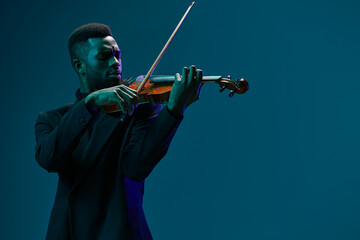 Elegant musician performing classical music on violin in a formal attire against vibrant blue...
