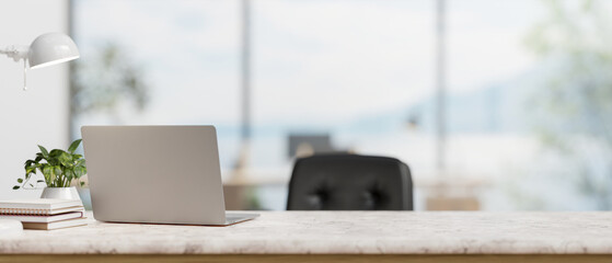 A back view image of a laptop computer on a white marble desk in a modern spacious office. - obrazy, fototapety, plakaty