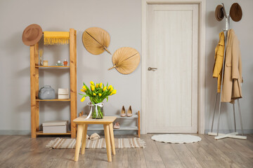 Shelving unit with vase of yellow tulips in hallway